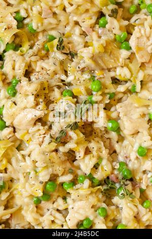 Nahaufnahme von cremigem Risotto-Reis mit Lauch, Huhn, Speck und Erbsen. Stockfoto