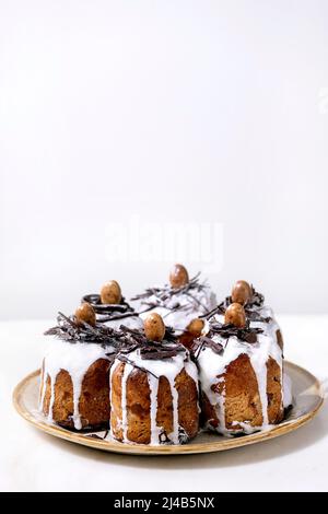 Hausgemachte traditionelle Ostern kulich Kuchen mit Schokolade Nester und Eier auf Keramikplatte über weißem Textur Hintergrund. Traditionelles ortodoxes Osterrussi Stockfoto