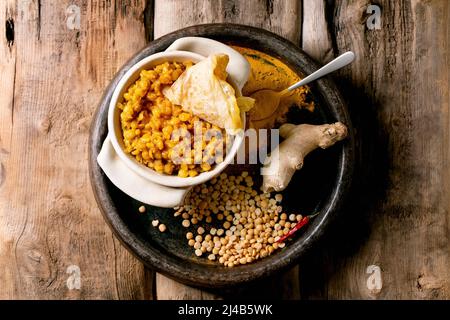 Dhal mit Roti-Brot. Traditionelles indisches Gericht aus gelber Erbse mit Roti-Fladenbrot, serviert mit Zitrone in einer Keramikschale auf einem alten Holztisch. Flach liegend, Polizist Stockfoto
