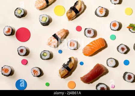 Sushi-Brötchen im Set. Traditionelles japanisches Sushi und Brötchen mit frischem Lachs, Thunfisch, Aal und Garnelen auf Reis, bunte Kreise auf beigem Hintergrund mit Stockfoto