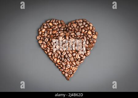 Kaffeebohnen in Herzform auf dunklem rustikalem Hintergrund, flacher Lay Stockfoto