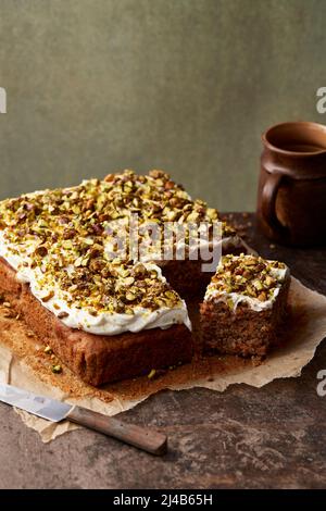Karottenkuchen mit Frischkäse-Zuckerguss und karamellisierten Pistazien Stockfoto