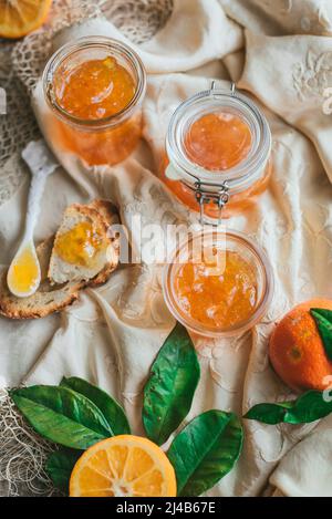 Hausgemachte Sevilla Orangenmarmelade in einem Glas mit geschnittenen Orangen Stockfoto