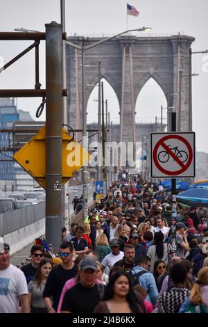 Touristen kommen wieder nach New York City. Am 13. April 2022 läuft eine große Menschenmenge über die Brooklyn Bridge in New York City. Stockfoto