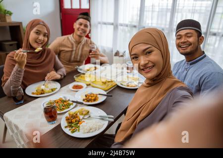 asiatische muslimische Freund machen Selfie zusammen mit Smartphone, während iftar Abendessen Stockfoto