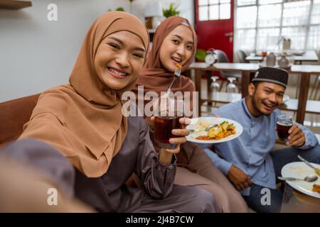 asiatische muslimische Freund machen Selfie zusammen mit Smartphone, während iftar Abendessen Stockfoto