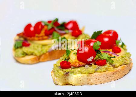 Gesundes, offenes veganes Sandwich mit Avocado-Maische, Zucchini, Kirschtomaten, Käse auf Maisbrot. Gesundes Essen, vegetarisches Konzept Stockfoto