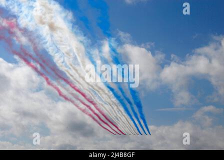 Das Aerobatic-Team der RAF Red Arrows fliegt in die Ferne und hinterlässt Spuren von rotem, weißem und blauem Rauch Stockfoto