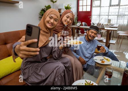 asiatische muslimische Freund machen Selfie zusammen mit Smartphone, während iftar Abendessen Stockfoto