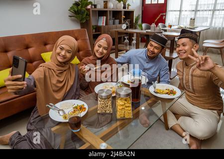 asiatische muslimische Freund machen Selfie zusammen mit Smartphone, während iftar Abendessen Stockfoto