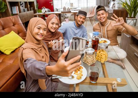 asiatische muslimische Freund machen Selfie zusammen mit Smartphone, während iftar Abendessen Stockfoto