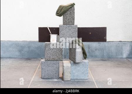 Spontane Kunstinstallation mit Ziegeln, einem Holzbrett, einem Paar Socken und einem Löffel in einem Joghurtpaket Stockfoto