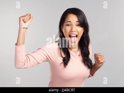 Haben dies getan. Aufnahme einer schönen jungen Frau, die fröhlich aussieht, während sie vor einem grauen Hintergrund steht. Stockfoto