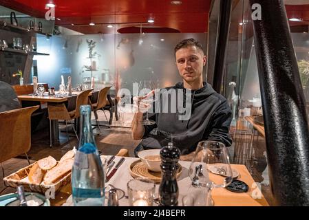 Junger Mann mit Sektglas am Tisch serviert mit Speisen im Restaurant Stockfoto