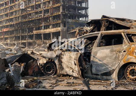 Nach der Shell von Zivilisten bombardiert Stadt Schaden Auto. 2022 Russische Invasion der Ukraine Krieg zerrissene Stadt zerstört Auto brennen aus. Bombe Angriff Russland Krieg Stockfoto