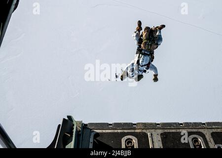 Naval Special Warfare-Mitglieder führen während der Arctic Edge Übung 2022 einen hoch gelegenen Sprung mit geringer Öffnung durch. Arctic Edge ist eine zweijährige Verteidigungsübung der Northern Command der USA, die die Fähigkeit zum schnellen Einsatz und Einsatz in der Arktis demonstrieren und ausüben soll. (USA Navy Photo von Mass Communication Specialist 2. Class Trey Hutcheson) Stockfoto