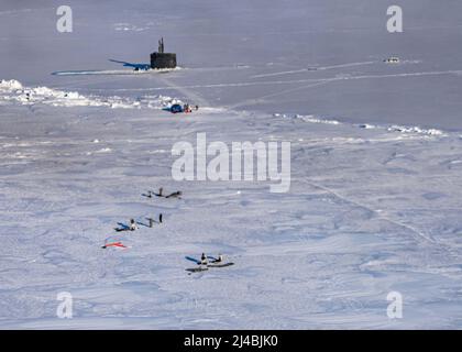 Naval Special Warfare-Mitglieder führen in ICEX einen hochgelegenen Sprung mit geringer Öffnung über das Schnellangriffs-U-Boot USS Pasadena (SSN 752) der Los Angeles-Klasse durch, der zeitgleich mit der Arctic Edge-Übung 2022 stattfand. Arctic Edge ist eine zweijährige Verteidigungsübung der Northern Command der USA, die die Fähigkeit zum schnellen Einsatz und Einsatz in der Arktis demonstrieren und ausüben soll. (USA Navy Photo von Mass Communication Specialist 2. Class Trey Hutcheson) Stockfoto
