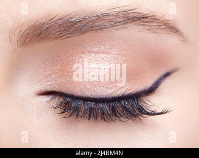 Nahaufnahme einer Makroaufnahme eines weiblichen geschlossenen Auges. Frau mit natürlichen Mode Gesicht Schönheit Make-up. Mädchen mit perfekter Haut und hellrosa Augen Schatten. Stockfoto