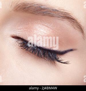 Nahaufnahme einer Makroaufnahme eines weiblichen geschlossenen Auges. Frau mit natürlichen Mode Gesicht Schönheit Make-up. Mädchen mit perfekter Haut und hellrosa Augen Schatten. Stockfoto