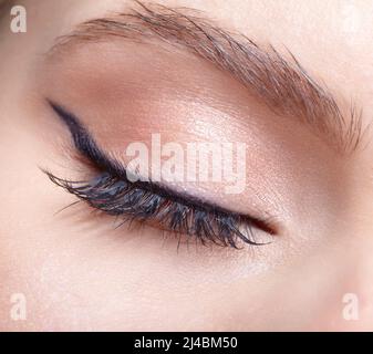Nahaufnahme einer Makroaufnahme eines weiblichen geschlossenen Auges. Frau mit natürlichen Mode Gesicht Schönheit Make-up. Mädchen mit perfekter Haut und hellrosa Augen Schatten. Stockfoto