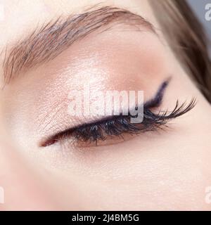 Nahaufnahme einer Makroaufnahme eines weiblichen geschlossenen Auges. Frau mit natürlichen Mode Gesicht Schönheit Make-up. Mädchen mit perfekter Haut und hellrosa Augen Schatten. Stockfoto