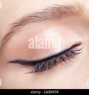 Nahaufnahme einer Makroaufnahme eines weiblichen geschlossenen Auges. Frau mit natürlichen Mode Gesicht Schönheit Make-up. Mädchen mit perfekter Haut und hellrosa Augen Schatten. Stockfoto