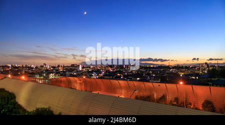 Sonnenuntergang über Schallschutzbarrieren auf der Autobahn, die durch das Stadtgebiet verläuft Stockfoto