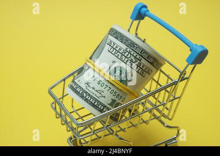 In einen Schlauch gerollte Dollars liegen in einem Einkaufskorb. Stockfoto