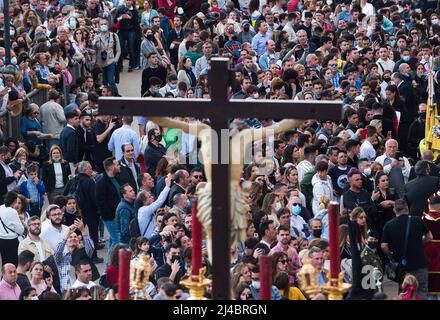 Malaga, Spanien. 13. April 2022. Faithfuls werden gesehen, wie sie die Statue von Christus betrachten, während die Büßer der Bruderschaft „Fusionadas“ während des Karmittwochs einen kunstvollen Festwagen tragen, um die Feierlichkeiten der Karwoche zu feiern. Nach zwei Jahren ohne Karwoche aufgrund der Coronavirus-Pandemie warten Tausende von Gläubigen darauf, die Prozessionen mit den Statuen von Christus und der Jungfrau Maria im Rahmen der traditionellen Karwoche auf den Straßen zu sehen. Kredit: SOPA Images Limited/Alamy Live Nachrichten Stockfoto