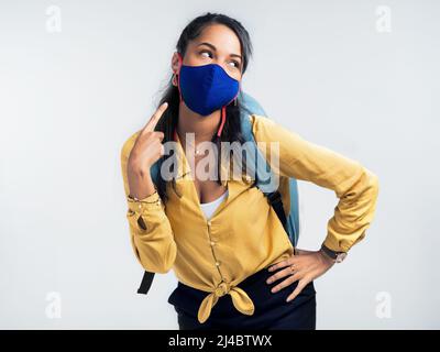 Maskiert und bereit für ein Abenteuer. Studioaufnahme einer Frau, die auf ihre Maske zeigt, während sie vor einem weißen Hintergrund steht. Stockfoto