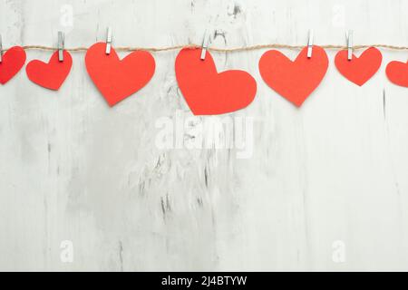 Valentine Hintergrund mit roten Herzen auf Wäscheklammern auf weißem Hintergrund. Happy Baby Tageskarte im Nachbau, Platz zum Kopieren Stockfoto