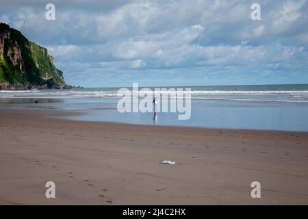 Ein Fischer läuft am Strand entlang Stockfoto