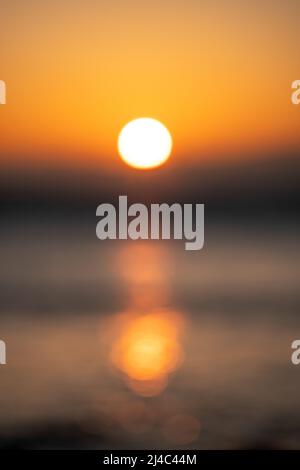 Abstrakte Natur Sommer oder Frühling Meer Meer Hintergrund. Kleine Wellen auf der goldenen, warmen Wasseroberfläche verwischen sich in Bewegung mit Bokeh-Lichtern vom Sonnenaufgang. Urlaub Stockfoto