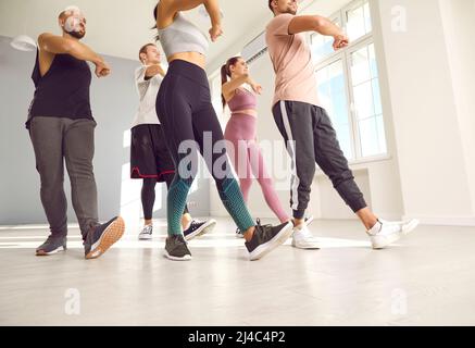 Eine Gruppe von jungen, fit trainingsfreien Menschen, die einen Tanz- oder Fitnesskurs mit einem Trainer absolvieren Stockfoto