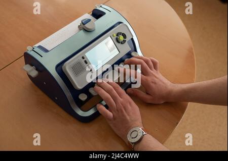 Blinder Mann mit Brailleschrift-Schreibmaschine. Stockfoto