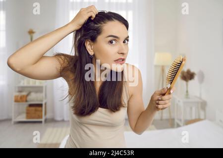 Junge Frau ist durch Anzeichen von Haarausfall Angst oder gestresst wegen der Kopfhautschuppen Stockfoto