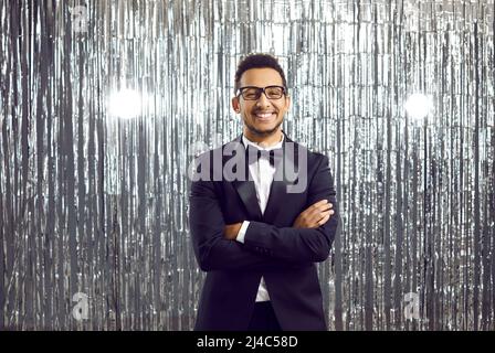 Fröhlicher, hübscher junger schwarzer Gentleman in einem eleganten Smoking und einer Brille auf einer Party Stockfoto