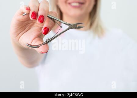 Die Cuticuspinzette. Hände halten ein Maniküre- und Pediküre-Werkzeug. Speicherplatz kopieren. Konzept Der Schönheitsindustrie Stockfoto