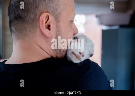 Przemysl, Polen. 12. April 2022. Radoslaw Fedaczynski, Tierarzt, hält einen Monat alten ziegenbock Sasha in seinen Armen in der Tierklinik „Ada“. Billy Goat Sasha kam aus dem Gebiet um die ukrainische Stadt Lemberg mit beschädigten Vorderhufen. Mit den schiefen Beinen konnte er am Euter nicht trinken. Unter anderem wurden mit Hilfe von Schienen seine Vorderbeine begradigt, so dass er wieder gehen konnte. In der Klinik in Przemysl, Polen, behandeln Tierärzte und Tierpfleger kranke und verletzte Tiere aus der Ukraine. Quelle: Christoph Soeder/dpa/Alamy Live News Stockfoto