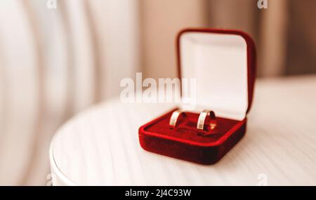 Hochzeitsringe aus Gold in roter Samtbox auf dem Tisch Stockfoto