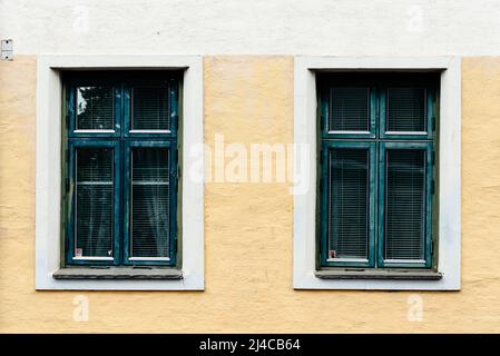 Zwei alte, grün gestrichene Holzfenster an der Stuckfassade. Stockfoto