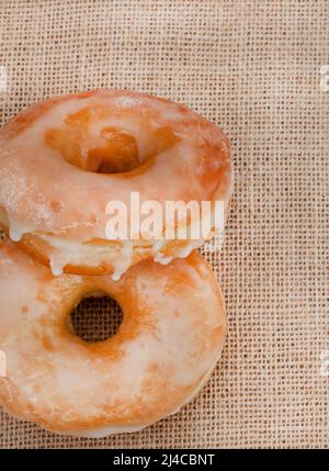 Zwei schlichte glasierte Donuts auf rustikaler Oberfläche mit Kopierfläche Stockfoto