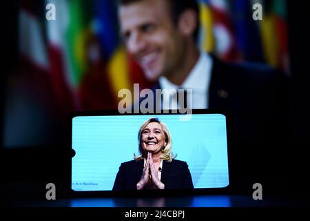 Marine Le Pen steht vor einem Fernsehbildschirm. Präsidentschaftswahlen in Frankreich 2022. Frankreichs Präsident Emmanuel Macron vor dem Hintergrund seiner Oppon Stockfoto