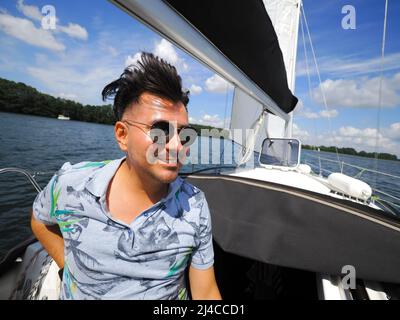 Lächelnd eine Erwachsene Person auf einem Segelboot während seiner Yacht-Reise an einem sonnigen Sommertag Stockfoto