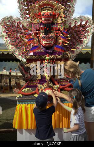 Frauen- und Kindertouristen achten auf eine traditionelle, skulpturale Kunst aus Reismehl als Opfergabe für spirituelle Zeremonien in Bedugul, Tabanan, Bali, Indonesien. Stockfoto