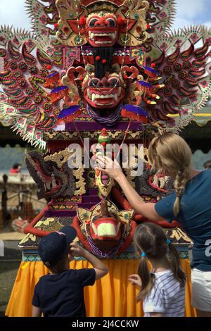 Frauen- und Kindertouristen achten auf eine traditionelle, skulpturale Kunst aus Reismehl als Opfergabe für spirituelle Zeremonien in Bedugul, Tabanan, Bali, Indonesien. Stockfoto