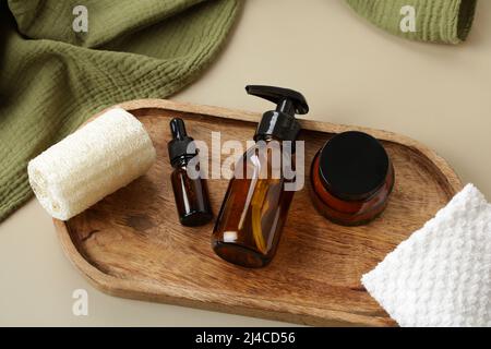 Set aus Bernstein-Glasflaschen mit Naturkosmetik auf Holztablett SPA, Bad Beauty-Produkte Verpackung Design. Stockfoto
