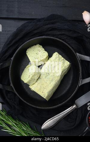 Portion Kräuterbutter mit Schnittlauch, Basilikum, Oregano, Petersilie-Set, auf schwarzem Holztisch-Hintergrund Stockfoto