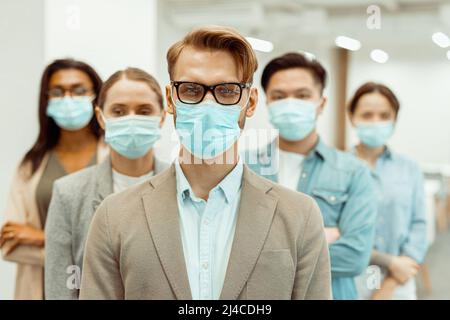 Multinationale Kollegen tragen Gesichtsschutzmasken Stockfoto
