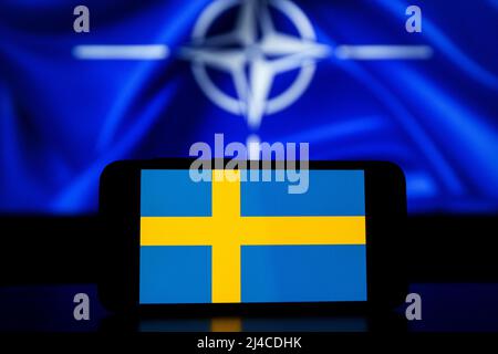 Die Organisation des Nordatlantikvertrags auf Bildschirmen. Schweden-Flagge auf dem Bildschirm und NATO-Flagge im Hintergrund Stockfoto